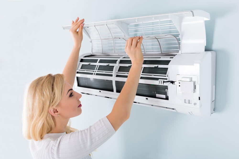 A Woman Checking Ductless Mini Split AC Unit