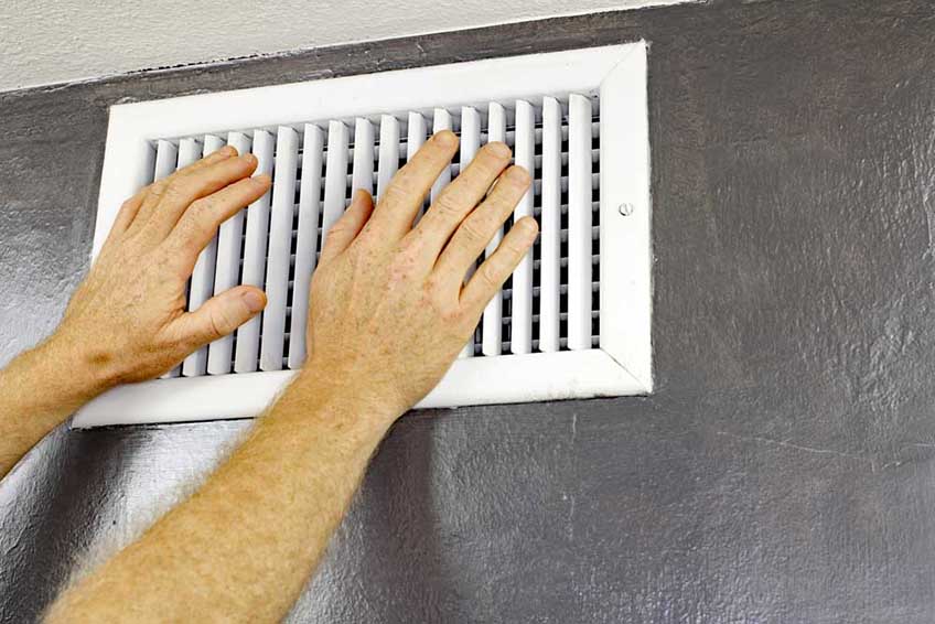 a person’s hand over HVAC vents