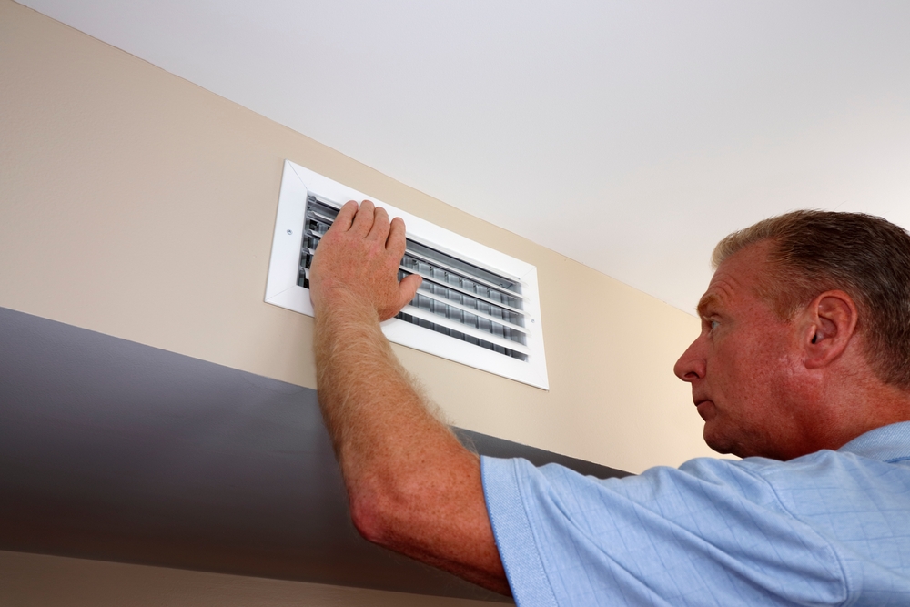 person’s hand checking the airflow from a vent