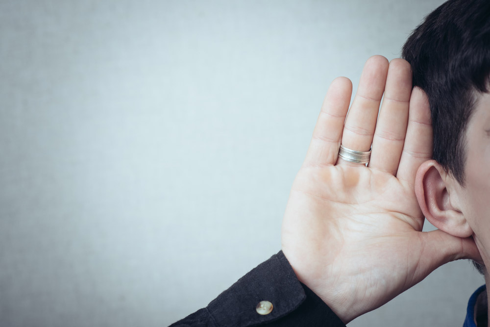 person with their open palm near their ear (trying to hear better)
